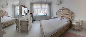 Ein Hotelzimmer mit zwei Betten, einem Schminktisch, einem Spiegel, einem Vorhangfenster und einer Klimaanlage.
