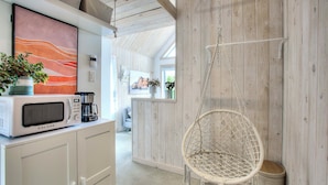Una cocina con microondas, una silla colgante y una pared de madera.