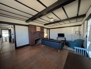 A spacious living room with a fireplace, a sofa, a television, and a dining area. - Home in 4th & Gill Near Downtown (Knoxville)