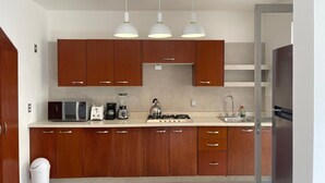 Une cuisine moderne avec des meubles en bois, un four à micro-ondes, une cuisinière et des luminaires suspendus.