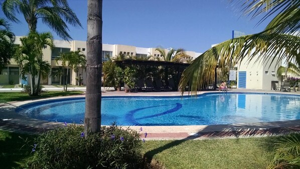 A swimming pool with a palm tree and a building in the background. - Casa Bahia Private Azul, Nayarit (Mezcales)