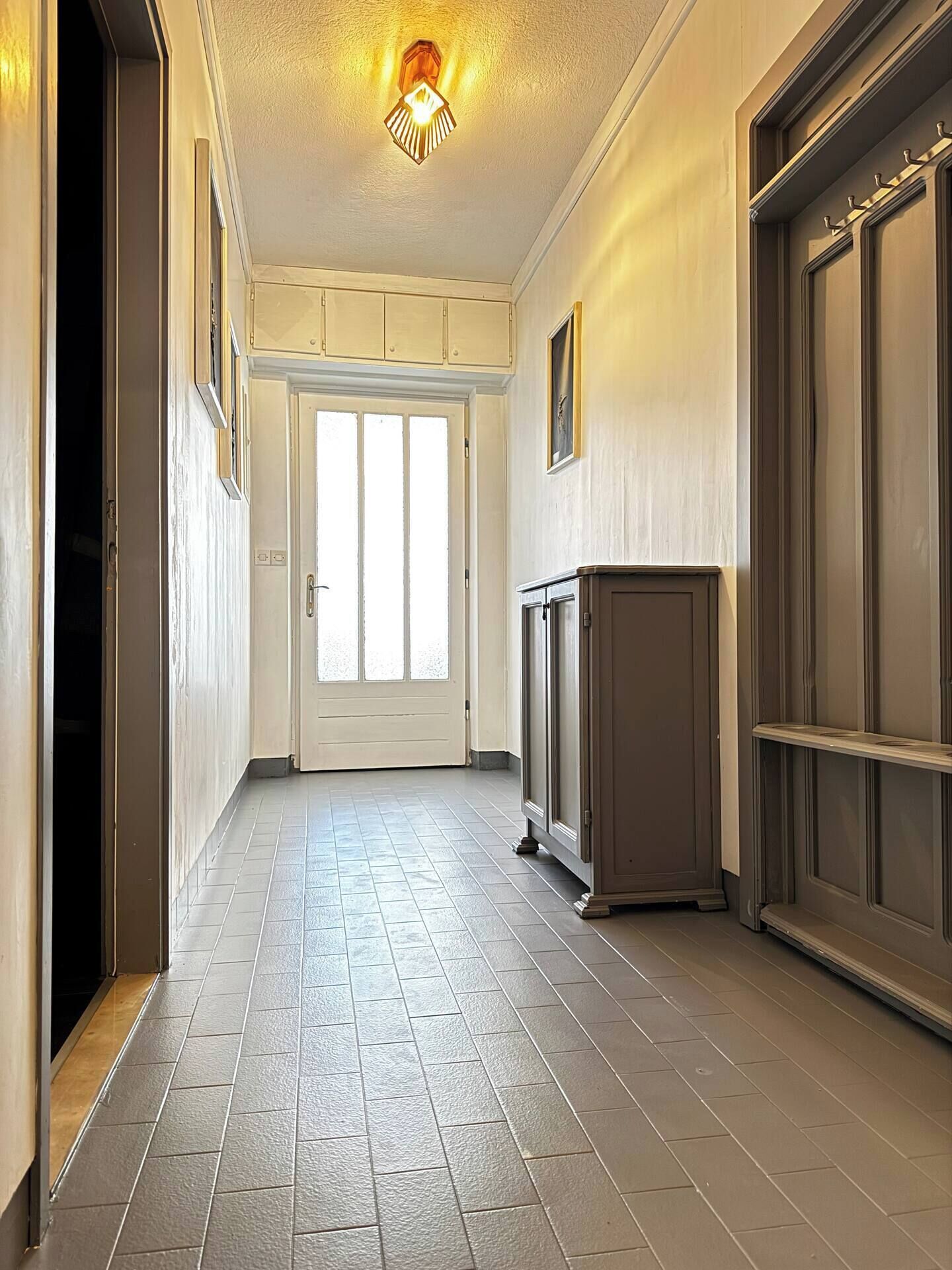 A hallway with a door, a light fixture, and a cabinet.