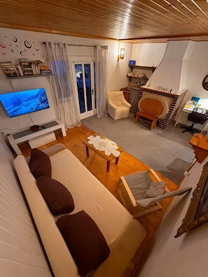 Ein Wohnzimmer mit einer Couch, einem Fernseher, einem Kamin und einem Essbereich.