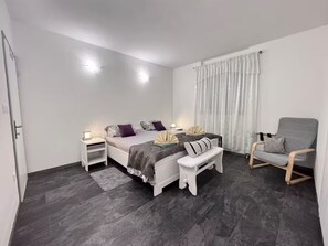 A modern bedroom with a bed, bedside tables, a bench, a chair, and a window with curtains. - Beautiful and spacious apartment Melani (Bol)