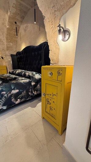Ein Schlafzimmer mit einem Bett, einer gelben Kommode und einer strukturierten Wand.