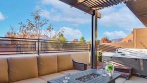 Eine Terrasse im Freien mit einer Couch, einem Tisch, einem Grill und einer Pergola.