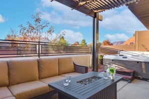 Eine Terrasse im Freien mit einer Couch, einem Tisch, einem Grill und einer Pergola.