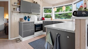 Una cucina moderna con mobili grigi, forno a incasso, piano di lavoro in granito e una finestra con vista sul verde.