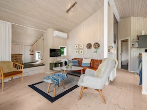 Ein gemütliches Wohnzimmer mit einer Couch, Sesseln, einem Couchtisch und einem Fernseher.