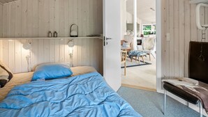 Una camera da letto con un letto, lampade sui comodini, un soffitto in legno e una porta che dà su un'area pranzo.