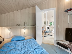 Ein Schlafzimmer mit einem Bett, Nachttischlampen, einer Holzboden und einer Tür zu einem Essbereich.