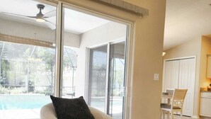 A modern living room with a sofa, a coffee table, and a view of a swimming pool.