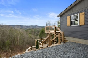 Ein Haus mit einer Holzterrasse und Blick auf einen bewaldeten Bereich.