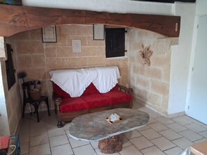 Ein gemütliches Zimmer mit einer roten Couch, einem Holztisch und einer Steinwand.