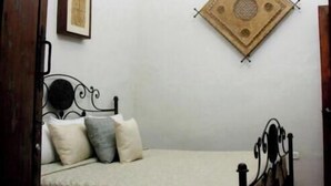 A bedroom with a bed, a wall-mounted decorative item, and a door.