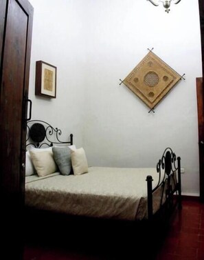 A bedroom with a bed, a wall-mounted decorative item, and a door. - CASA DE LOS DULCES SUEÑOS (Morelia)