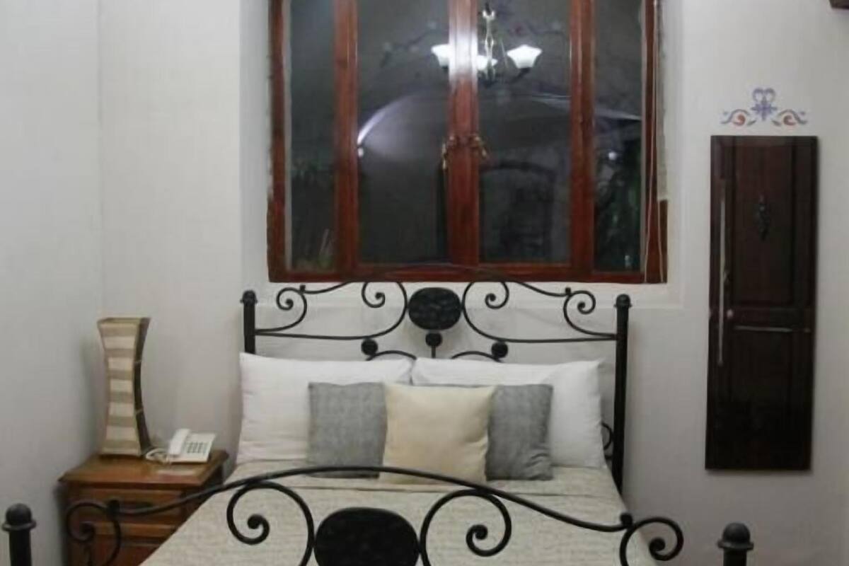 A bed with a metal frame, a wooden headboard, and a window above.