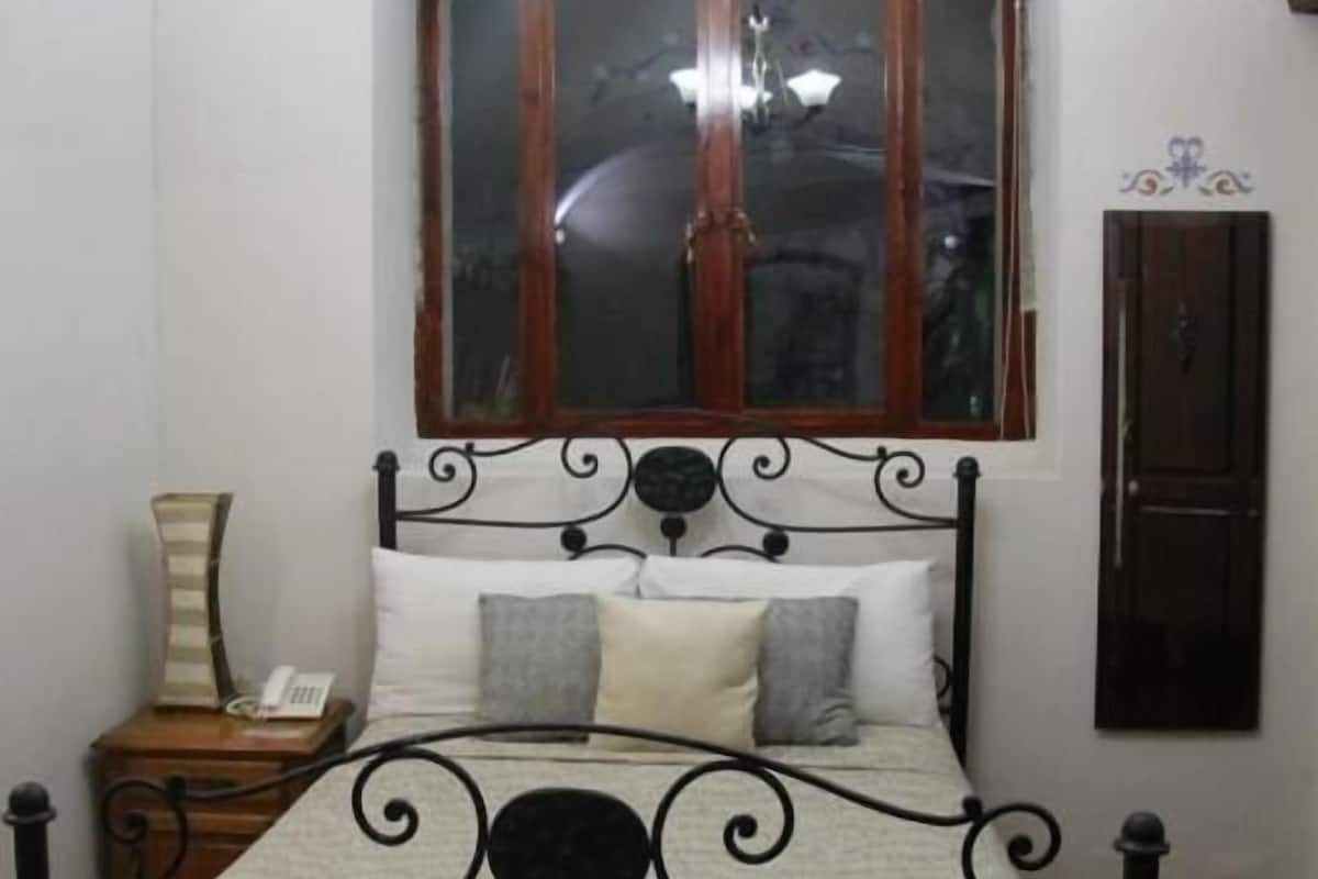 A bed with a metal frame, a wooden headboard, and a window above.