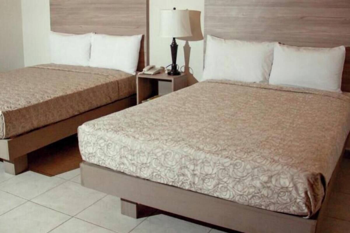 Two twin beds with patterned bedding, a bedside table with a lamp, and a phone.