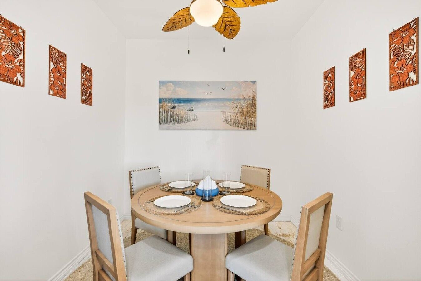 A dining area with a round table, chairs, and a ceiling fan.