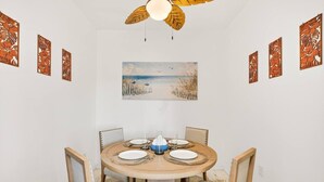 Zona pranzo con tavolo rotondo, sedie e ventola a soffitto.