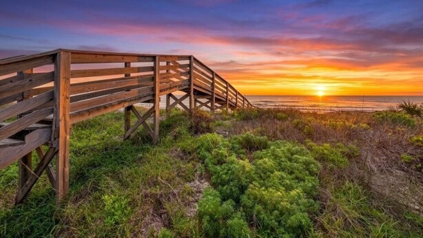 A wooden boardwalk leading to a beach with a sunset in the background. - Lux 2BR-2BA: Boardwalk + 3rd Floor Deck (Port Aransas)