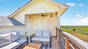 Un'area relax esterna coperta con pavimento in legno, una porta bianca e vista sul paesaggio.