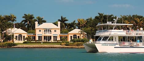 A large house with a pool and a boat named 'DOUBLE SUNSHINE' in the background.