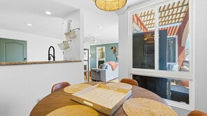 Ein stilvoller Essbereich mit einem runden Tisch, gewobenen Untersetzern und Blick auf einen Balkon mit einer Holzpergola.