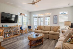 A living room with a television, a sofa, a wicker coffee table, and a bookshelf. - Wright Place Wright Time (Carolina Beach)