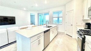 A modern kitchen with a central island, built-in oven, and a large window providing natural light. - Centrally-located coach home. (Punta Gorda)