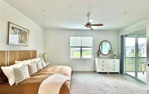 A bedroom with a bed, a ceiling fan, a window, a dresser, and a balcony. - Centrally-located coach home. (Punta Gorda)