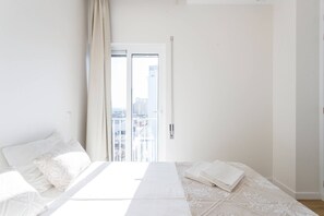A bedroom with a bed, a window, and a view of buildings. - Rocha Ocean View Apartment (Portimão)