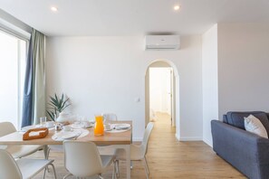 A modern living space with a dining area, a sofa, and an air conditioning unit. - Rocha Ocean View Apartment (Portimão)