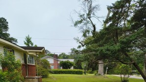A residential property with a well-maintained lawn, a brick house, and mature trees.