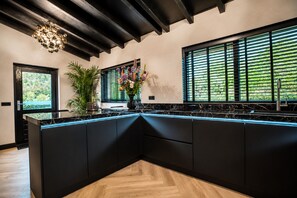 A modern kitchen with black cabinetry, a marble countertop, and a large island.