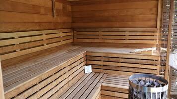 Un sauna en bois, avec des bancs et un cendrier en métal.