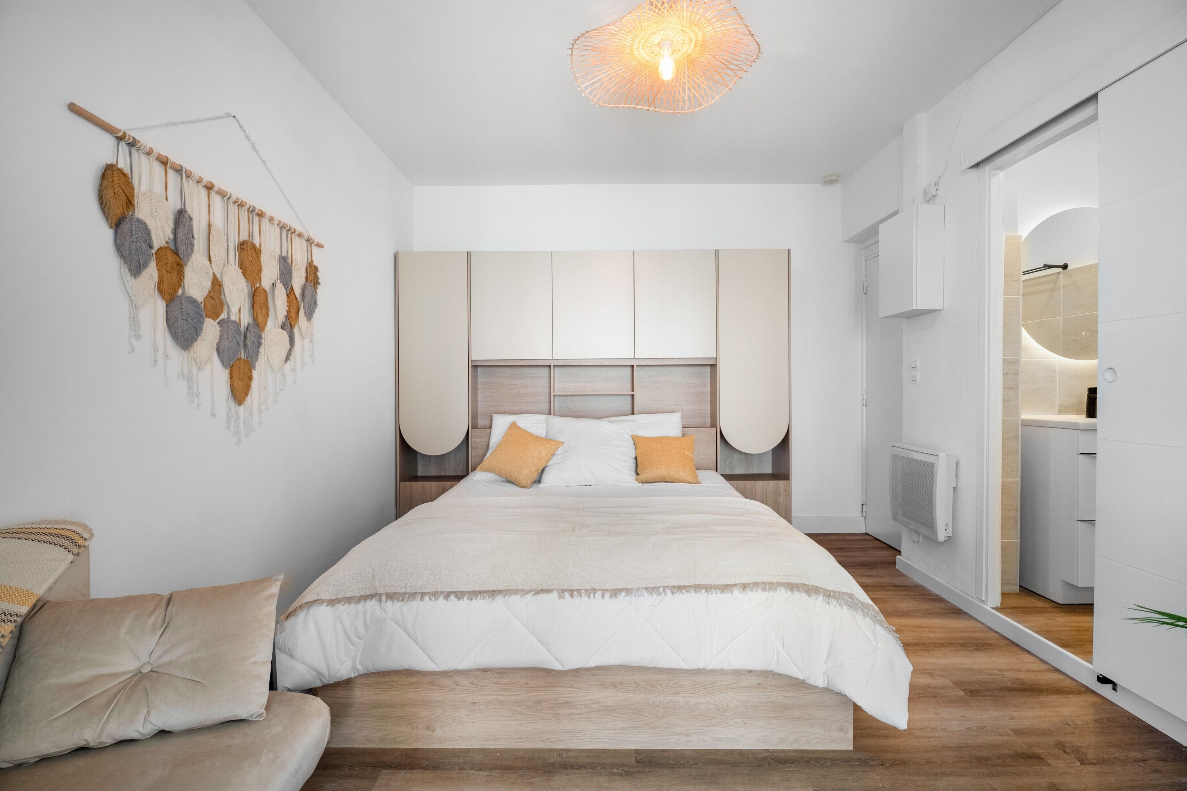 Ein modernes Schlafzimmer mit einem großen Bett, einer Wanddekoration aus Makramee und einem Einbauschrank.