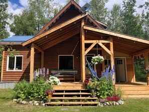 A wooden cabin with a porch, steps, and a window.