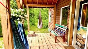 A wooden deck with a bench, a hanging bag, and a box of firewood. - Beautiful, private  2-bedroom cabin only a few miles from downtown Talkeetna (Talkeetna)