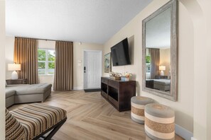 Ein Wohnzimmer mit Sofa, Hocker, Fernseher und einer Konsolentisch.
