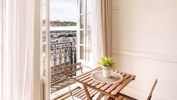 A balcony with a wooden table, a potted plant, and a view of a parking lot.