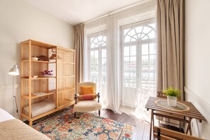 Ein Zimmer mit einer Holzhülle, einem Sessel, einem kleinen Tisch mit einer Pflanze und einem gemusterten Teppich.