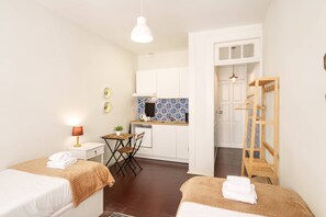 A compact hotel room with two beds, a small kitchenette, a wooden ladder, and a dining area. - VIVA Porto Tile Studios 3T (Porto)