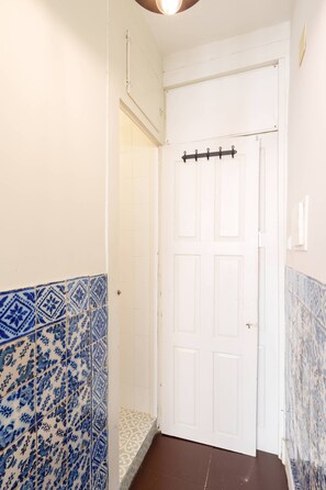 A hallway with a white door, blue patterned tiles on the walls, and a brown floor. - VIVA Porto Tile Studios 3T (Porto)