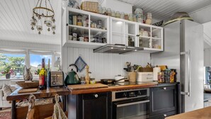 Una cucina con mobili bianchi, un piano di lavoro in legno, un forno e un frigorifero.