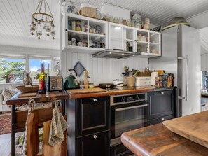 Eine Küche mit weißen Schränken, einer Holzarbeitsplatte, einem Herd und einem Kühlschrank.