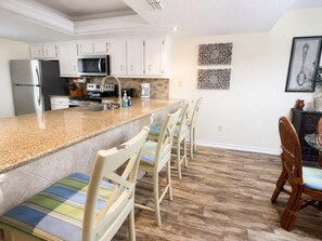 A kitchen with white cabinets, a granite countertop, and a stainless steel refrigerator. - Oceanfront Condo with Full Kitchen & Pet-Friendly (South Padre Island)