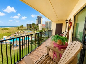 A balcony with a view of a pool and beach, a potted plant, and a chair. - Oceanfront Condo with Full Kitchen & Pet-Friendly (South Padre Island)