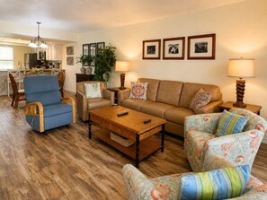 A living room with a sofa, armchairs, a coffee table, and a dining area with chairs and a table. - Oceanfront Condo with Full Kitchen & Pet-Friendly (South Padre Island)